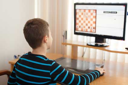 Teenage boy learning to play chess online with tablet computer